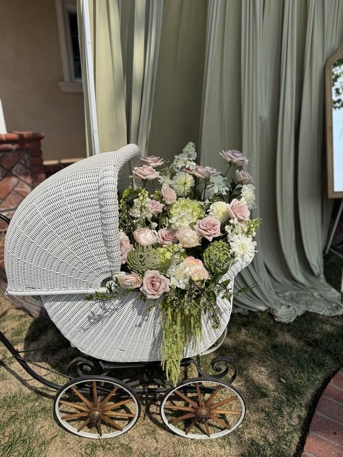 Vintage wicker baby carriage filled with blush pink and white florals